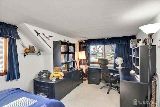 bedroom with light carpet and an office area
