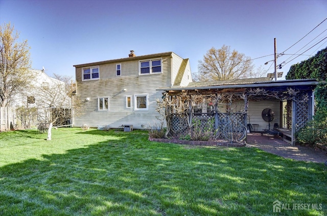 rear view of house featuring a chimney and a yard