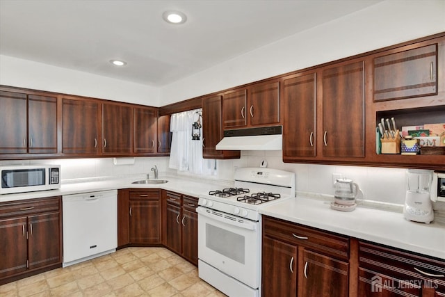 kitchen featuring white appliances, under cabinet range hood, a sink, light countertops, and recessed lighting