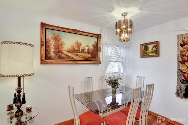 dining room with a chandelier, wood finished floors, and baseboards
