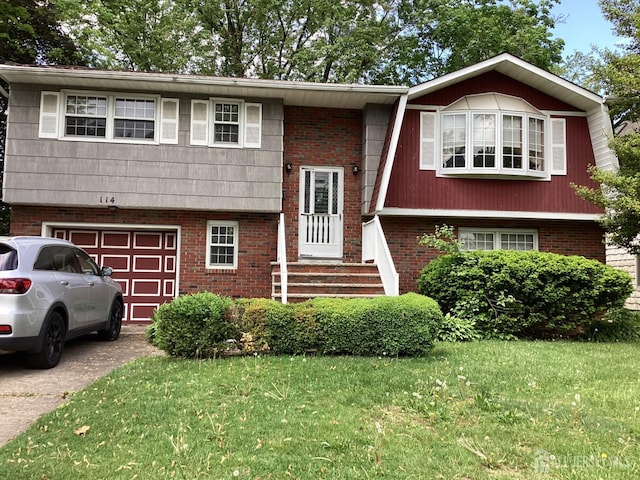 split foyer home with an attached garage, a front yard, driveway, and brick siding