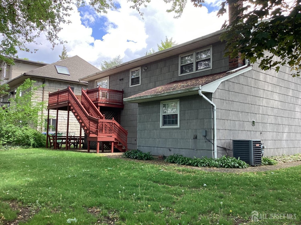 rear view of house with stairway, central air condition unit, a deck, and a lawn