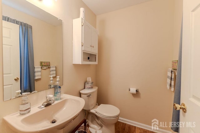 bathroom with wood finished floors, a sink, toilet, and baseboards