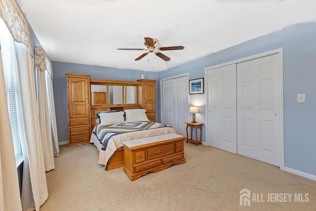 carpeted bedroom featuring two closets and ceiling fan