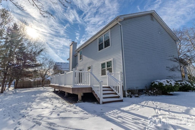 snow covered house with a wooden deck