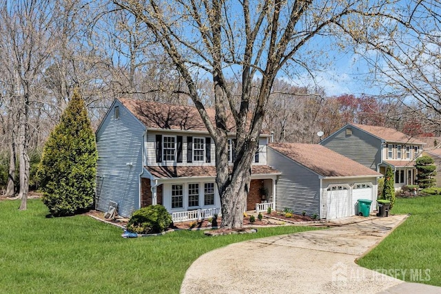 traditional-style home featuring driveway, covered porch, a front yard, and a garage