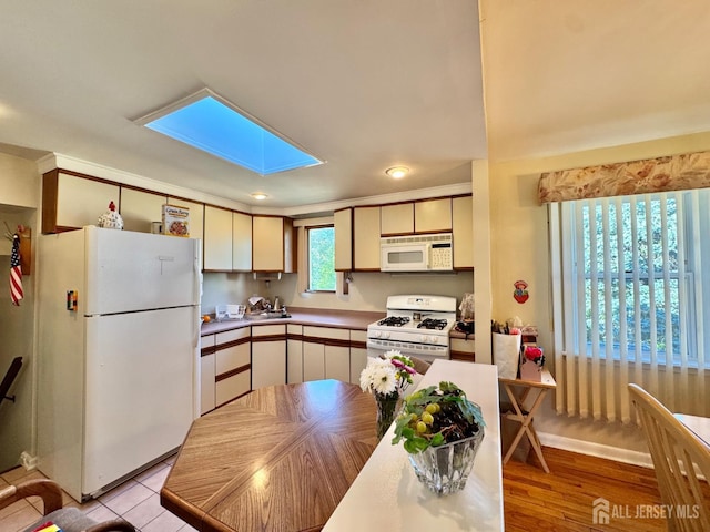 kitchen featuring white appliances, a skylight, light wood finished floors, and recessed lighting