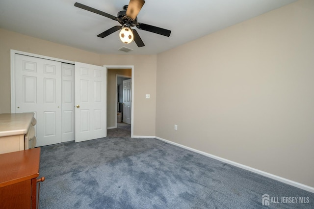 unfurnished bedroom with dark colored carpet, baseboards, a closet, and ceiling fan