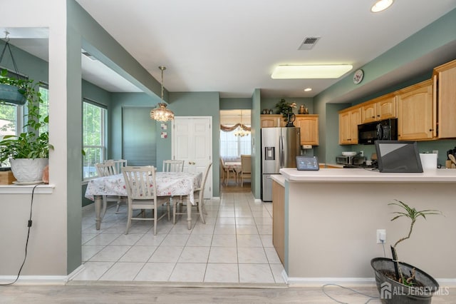 kitchen featuring black microwave, stainless steel refrigerator with ice dispenser, light countertops, a peninsula, and a chandelier