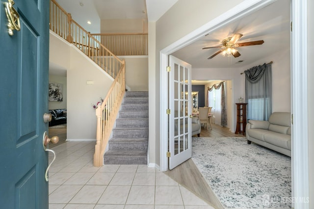 entrance foyer with stairway, a ceiling fan, baseboards, and light wood-style floors