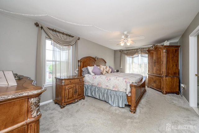 bedroom featuring light colored carpet, baseboards, and ceiling fan