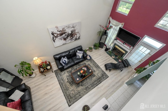 living area featuring wood finished floors, healthy amount of natural light, a high end fireplace, and a high ceiling