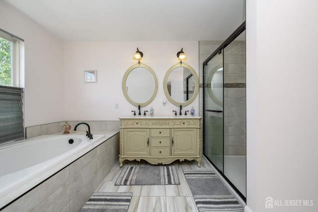 bathroom featuring a bath, a shower stall, double vanity, and tile patterned floors