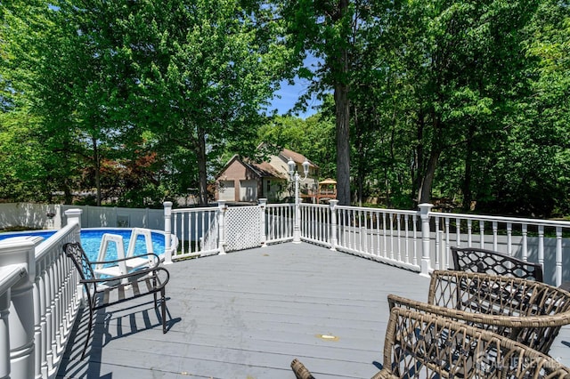 deck featuring fence and view of wooded area
