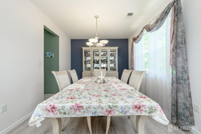 dining space featuring a chandelier, baseboards, and wood finished floors