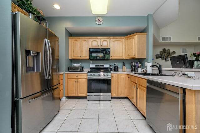 kitchen featuring stainless steel appliances, a sink, light tile patterned flooring, and light brown cabinets