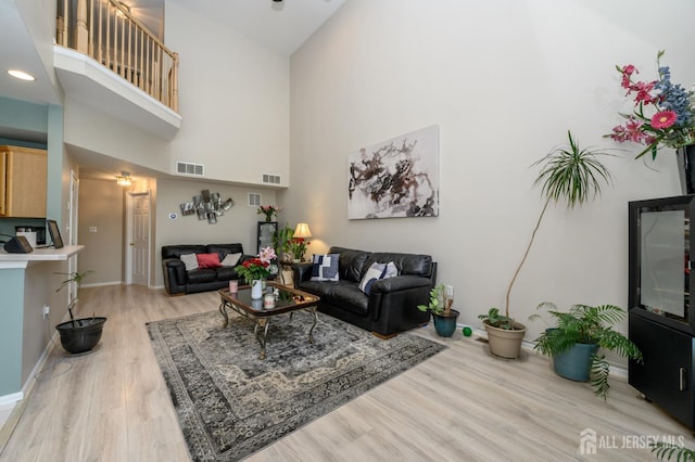 living room featuring a high ceiling, light wood-style flooring, and baseboards
