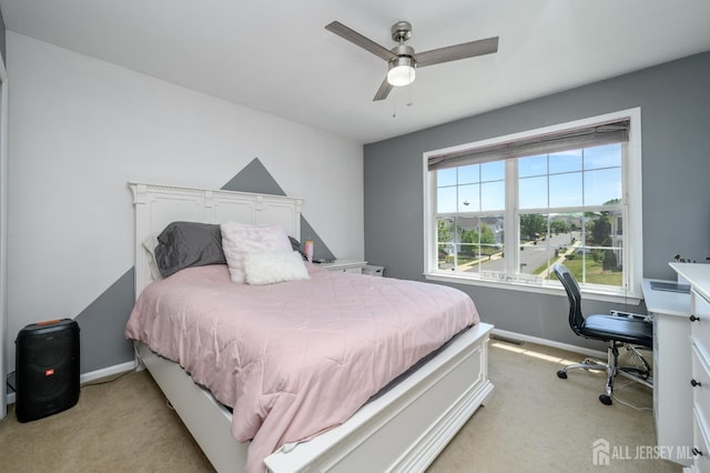 bedroom with light colored carpet, baseboards, ceiling fan, and a desk