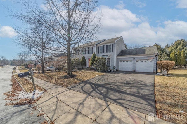 colonial inspired home with a garage and driveway