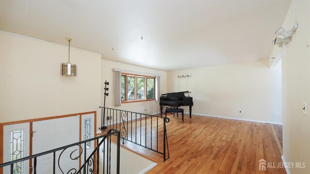 hallway with baseboards, an upstairs landing, and wood finished floors