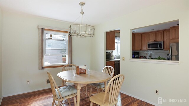 dining area featuring a chandelier, baseboards, and wood finished floors