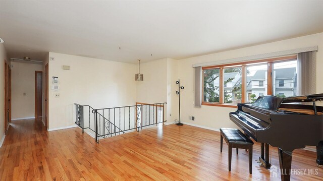 sitting room featuring baseboards, visible vents, an upstairs landing, and light wood-style floors