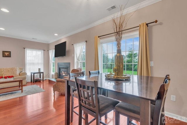 dining space featuring wood-type flooring and ornamental molding