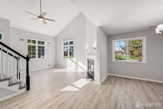 unfurnished living room with high vaulted ceiling, ceiling fan, and light wood-type flooring