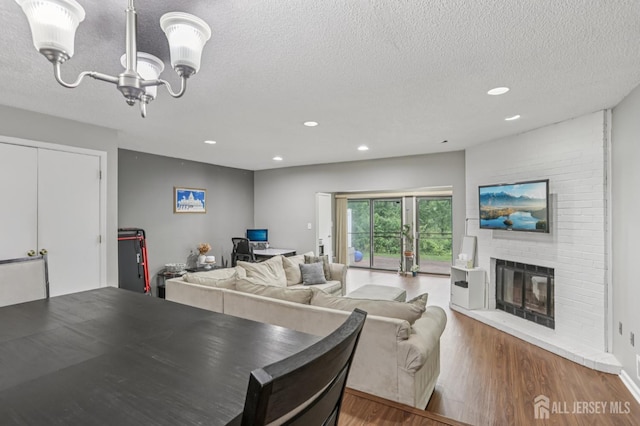 91 Pear Tree Ln, Franklin, NJ 08823 - dining room with a textured ceiling, recessed lighting, wood finished floors, a chandelier, and a brick fireplace
