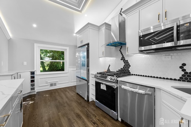4 Arden Rd, Old Bridge, NJ 08857 - kitchen featuring appliances with stainless steel finishes, wall chimney range hood, light stone counters, dark wood finished floors, and a wainscoted wall