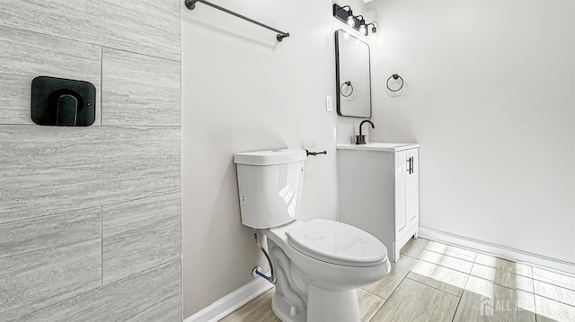 bathroom featuring toilet, baseboards, and vanity