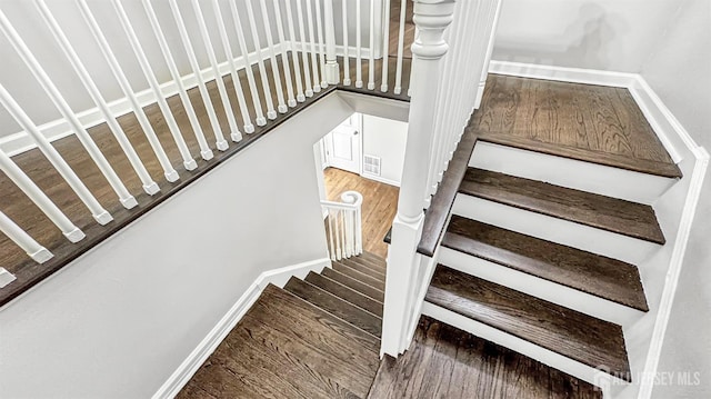 stairs with baseboards, visible vents, and wood finished floors