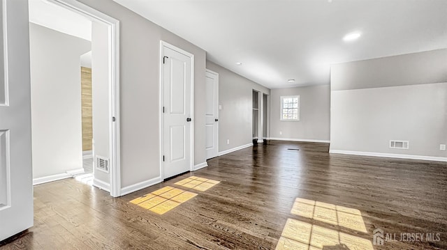 unfurnished room with dark wood-style floors, baseboards, visible vents, and recessed lighting