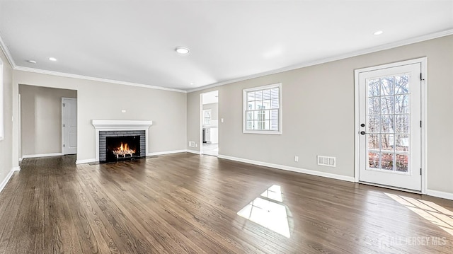 unfurnished living room featuring ornamental molding, dark wood-type flooring, baseboards, a fireplace, and recessed lighting