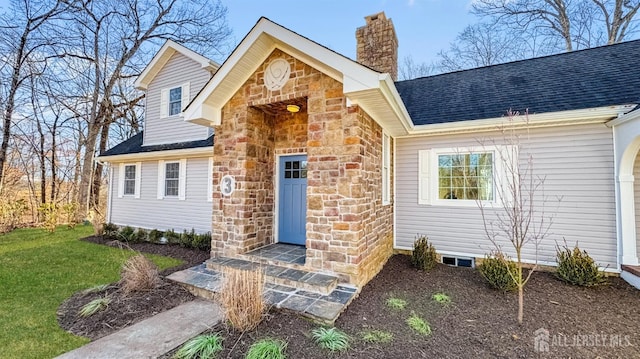 view of front of house featuring a chimney, stone siding, a front lawn, and a shingled roof