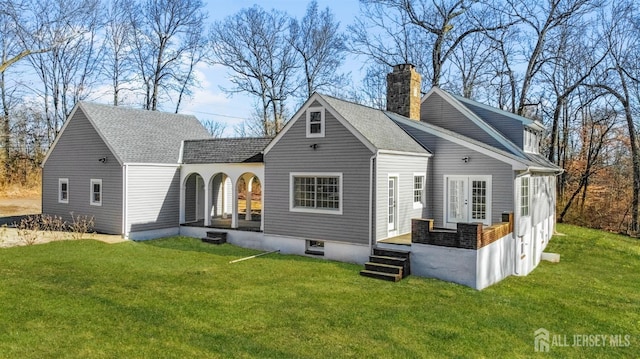 rear view of property with roof with shingles, a chimney, french doors, and a yard