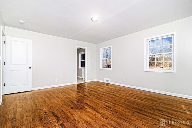 unfurnished room with dark wood-type flooring and baseboards