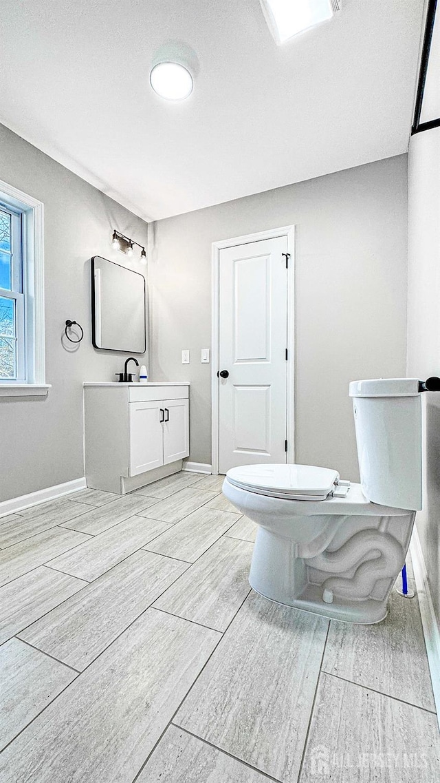 bathroom with toilet, baseboards, wood finished floors, and vanity