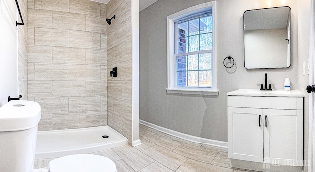 full bath featuring a stall shower, toilet, vanity, and baseboards