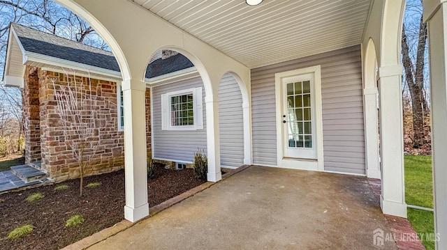 view of exterior entry with roof with shingles
