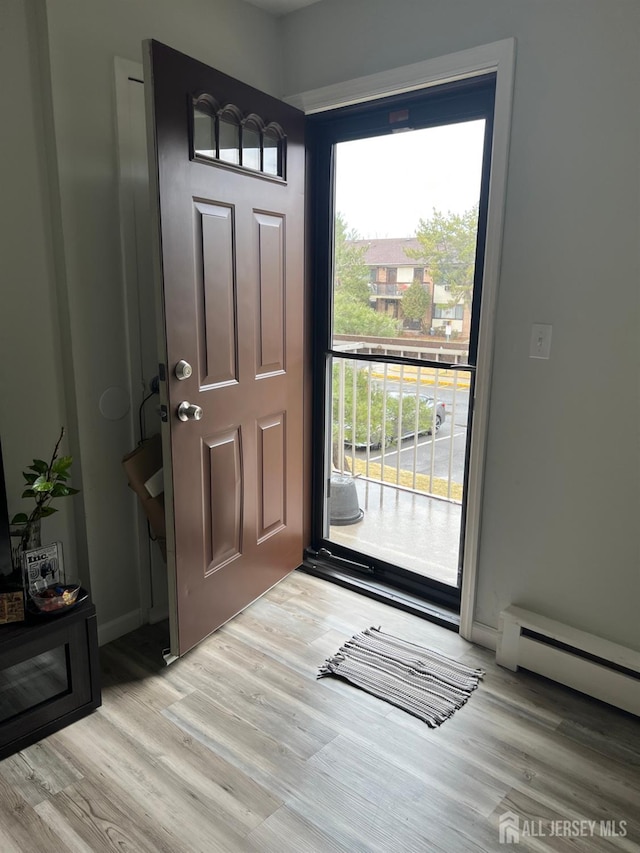 foyer featuring a baseboard heating unit, plenty of natural light, wood finished floors, and baseboards