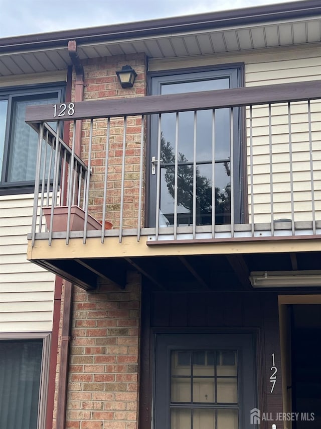 exterior space with brick siding and a balcony