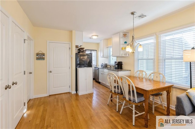 dining space with light hardwood / wood-style flooring and a notable chandelier