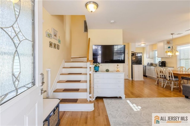 stairs with a chandelier and hardwood / wood-style floors