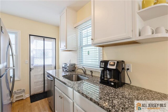 kitchen with light stone countertops, sink, white cabinets, and appliances with stainless steel finishes