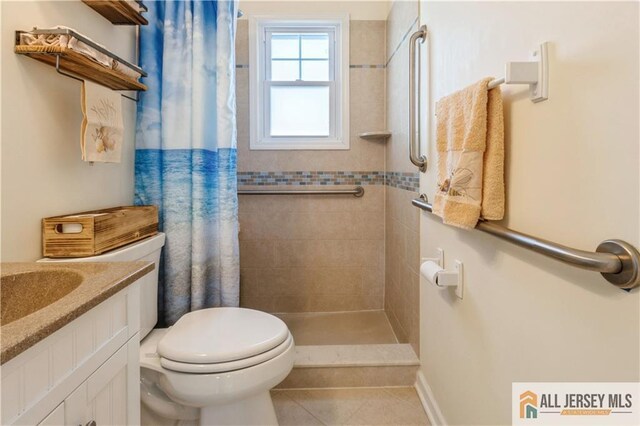 bathroom featuring toilet, vanity, a shower with curtain, and tile patterned flooring