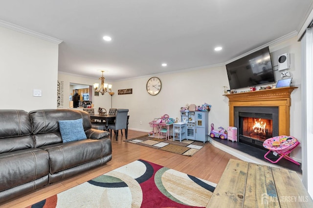 living room with light hardwood / wood-style floors, crown molding, and an inviting chandelier