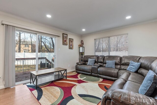 living room featuring a wealth of natural light, crown molding, and light hardwood / wood-style floors