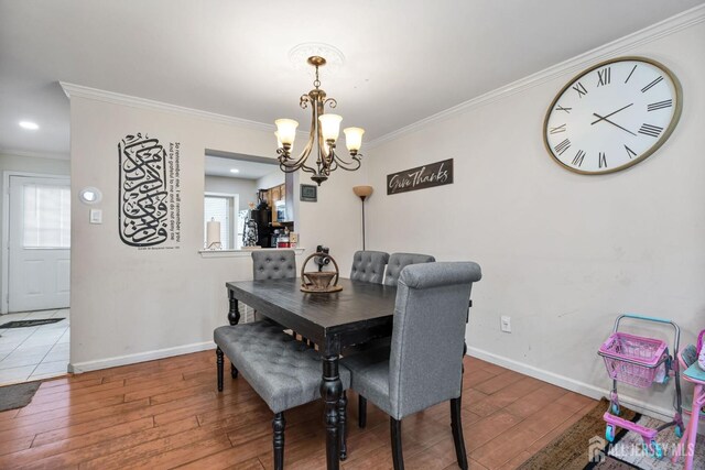 dining space with ornamental molding, hardwood / wood-style floors, and a notable chandelier