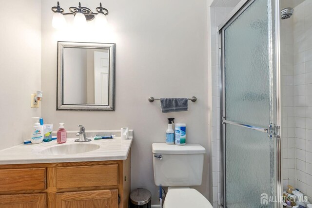 bathroom with toilet, vanity, and an enclosed shower